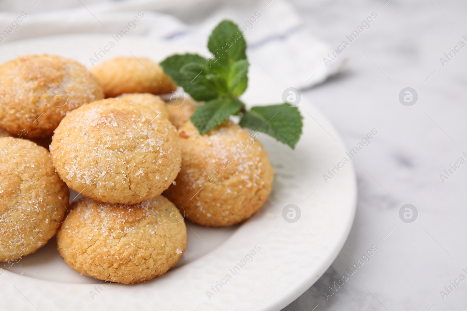 Photo of Tasty sweet sugar cookies and mint on white marble table, closeup