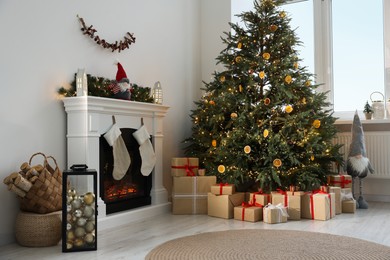 Many different gift boxes under Christmas tree and festive decor in living room