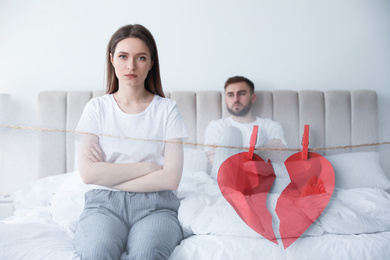 Image of Double exposure with unhappy couple with relationship problems and halves of torn paper heart pinned on laundry string