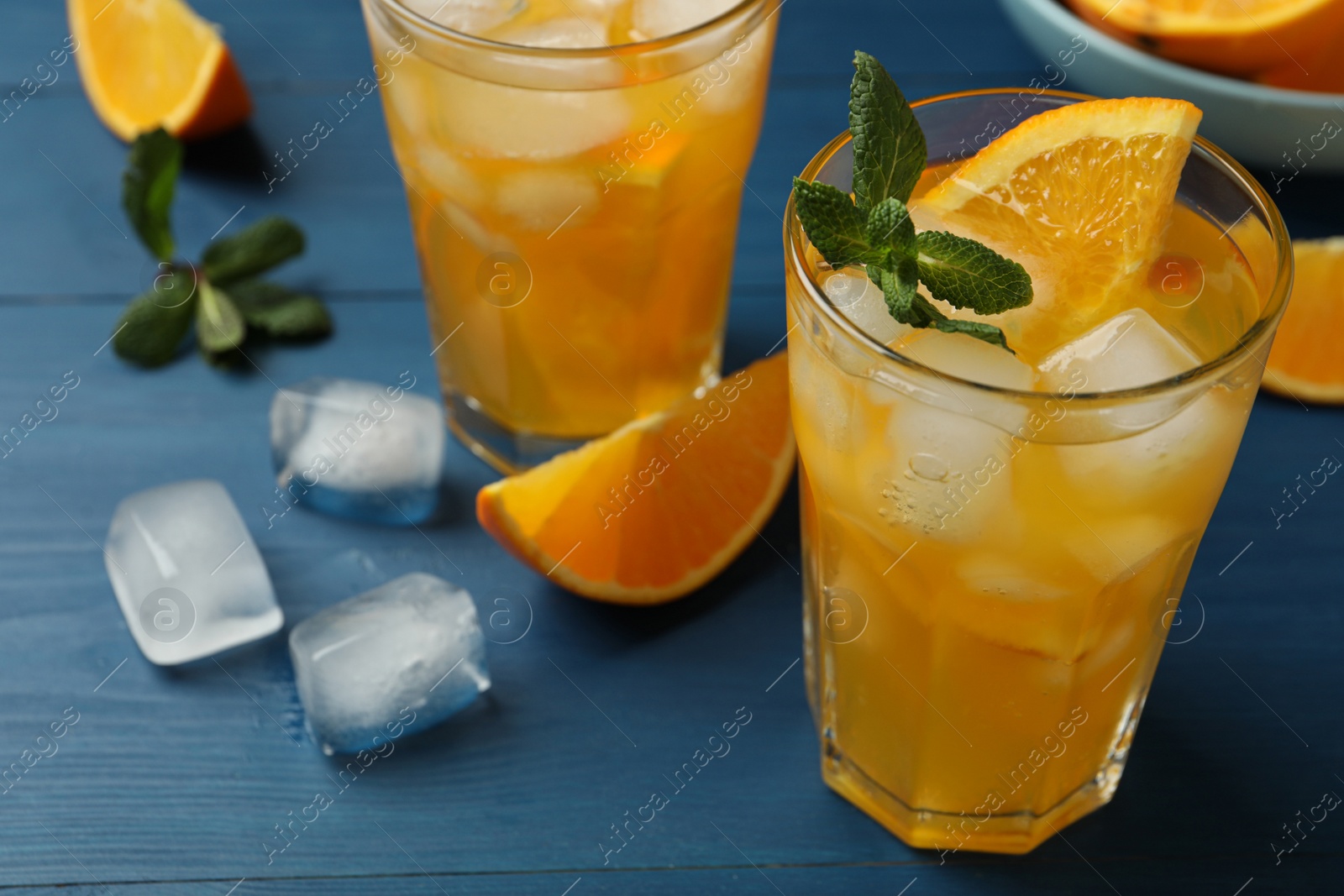 Photo of Delicious orange soda water on blue wooden table, closeup