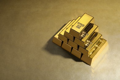 Photo of Many shiny gold bars on color background. Space for text