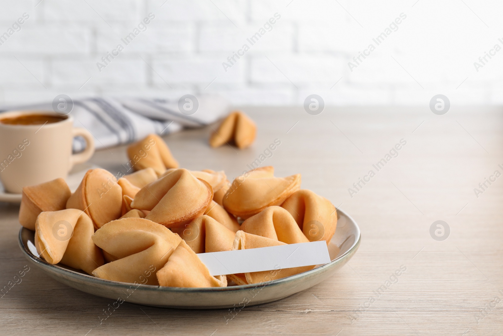 Photo of Tasty fortune cookies and paper with prediction on wooden table, space for text