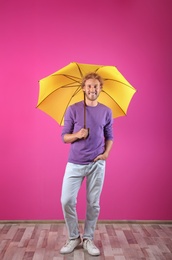 Photo of Man with yellow umbrella near color wall