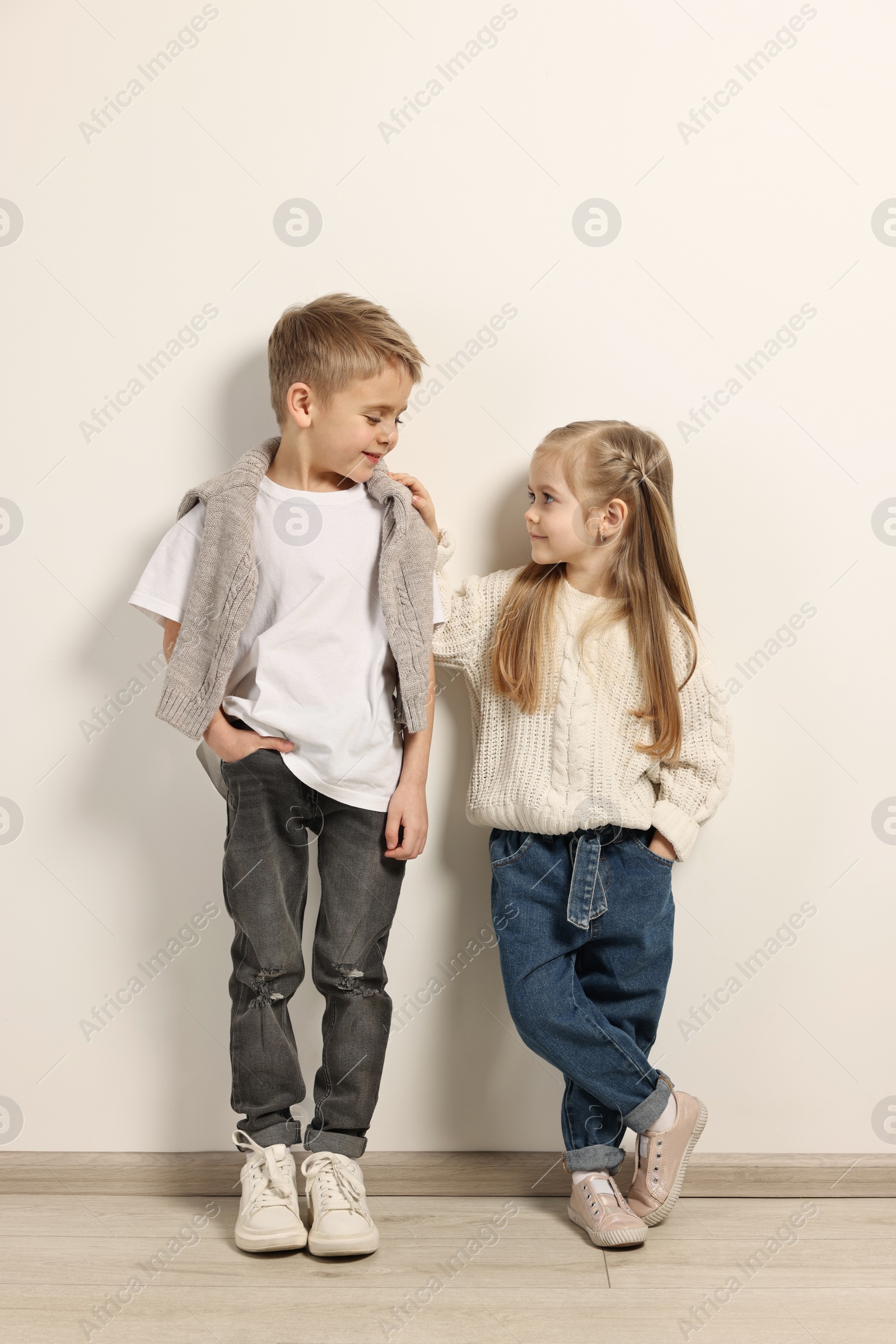 Photo of Fashion concept. Stylish children posing near white wall