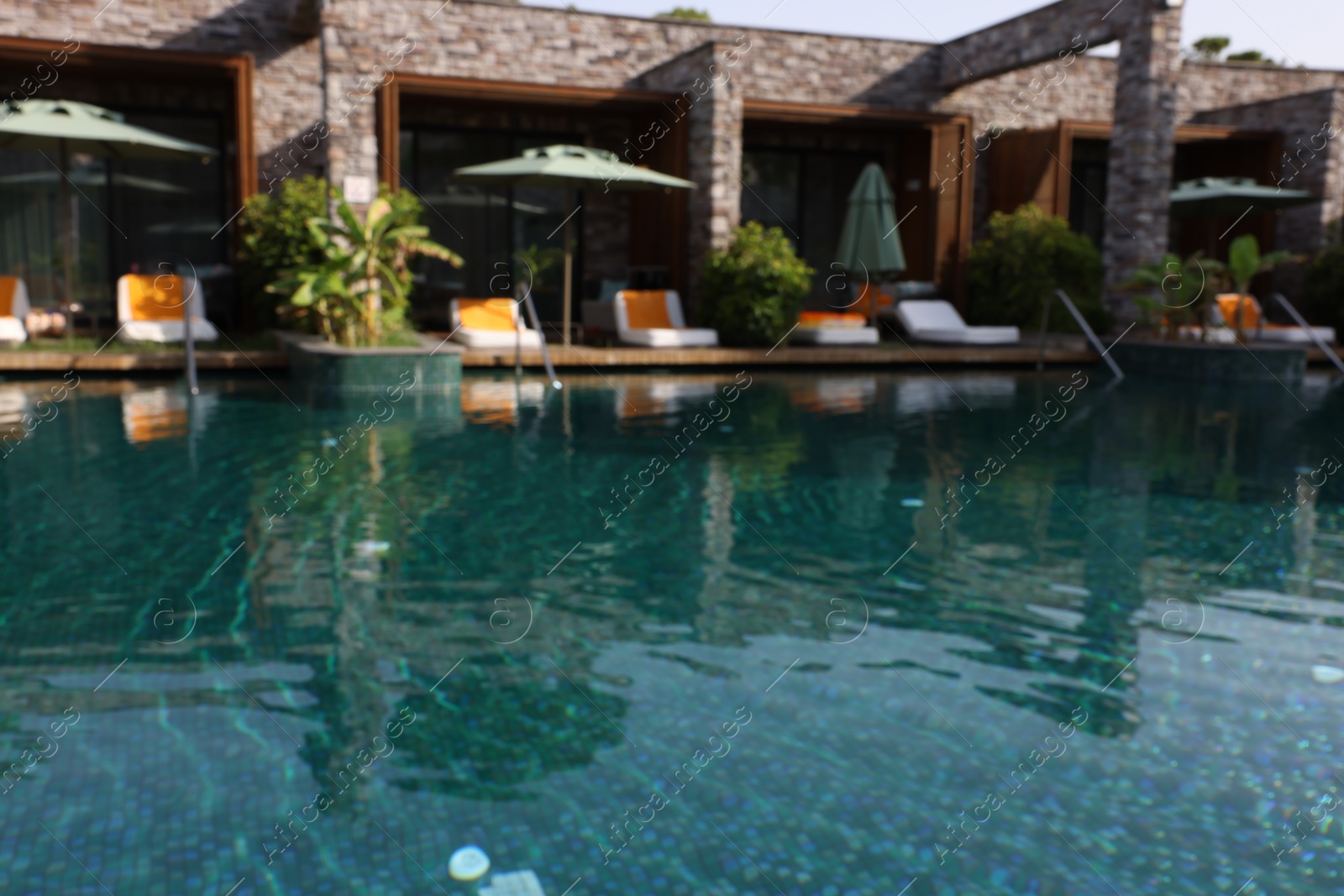 Photo of Blurred view of swimming pool, umbrellas and sunbeds at luxury resort