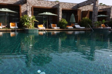 Photo of Blurred view of swimming pool, umbrellas and sunbeds at luxury resort