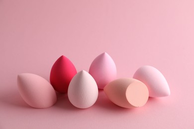 Photo of Many colorful makeup sponges on pink background