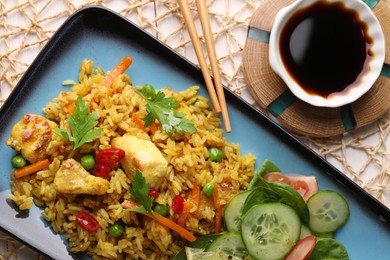 Photo of Tasty rice with meat and vegetables in plate near soy sauce on white table, flat lay