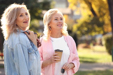 Photo of Happy mature women with coffee in park on sunny day