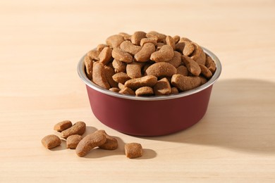 Photo of Dry dog food in pet bowl on wooden surface