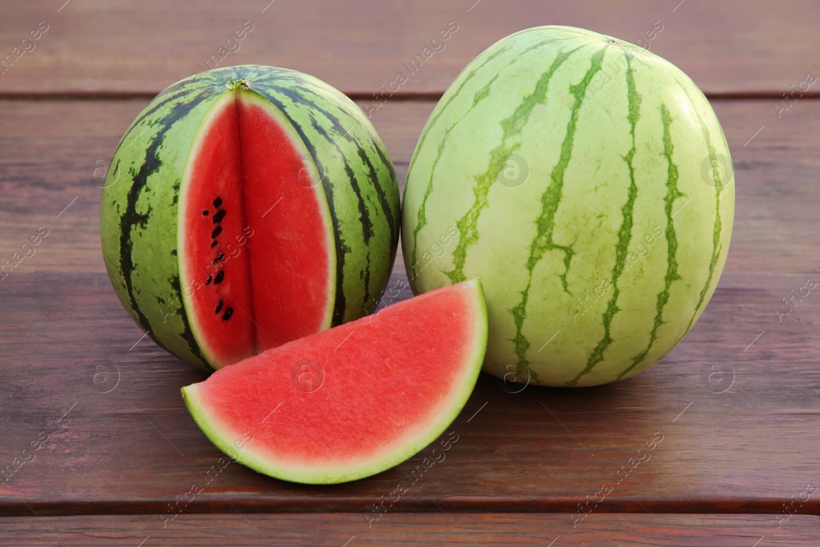 Photo of Different delicious ripe watermelons on wooden table