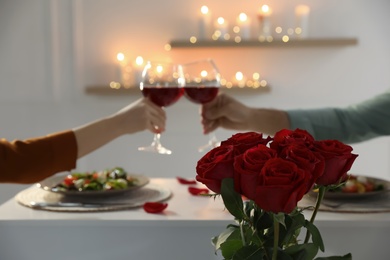 Photo of Couple having romantic dinner at home, focus on red roses