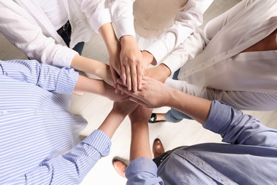 Photo of Group of people holding hands together indoors, above view. Unity concept