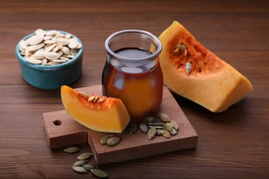 Photo of Fresh pumpkin seed oil in glass jar on wooden table