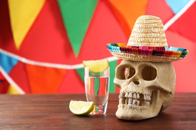 Photo of Human scull with Mexican sombrero hat and tequila on wooden table. Space for text