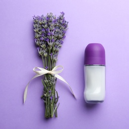 Female deodorant and lavender flowers on lilac background, flat lay