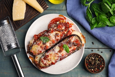 Baked eggplant with tomatoes, cheese and basil served on blue wooden table, flat lay