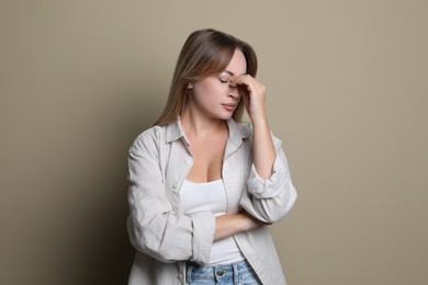 Photo of Young woman suffering from headache on beige background