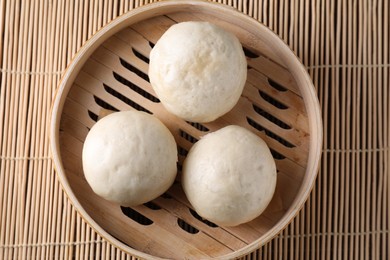 Photo of Delicious Chinese steamed buns on bamboo mat, top view