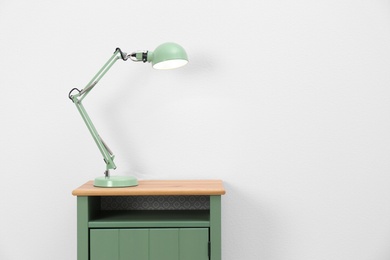 Stylish lamp on table against white background. Space for text