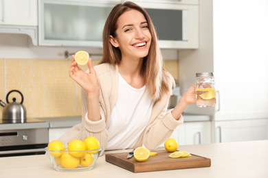 Young woman with mason jar of lemon water in kitchen