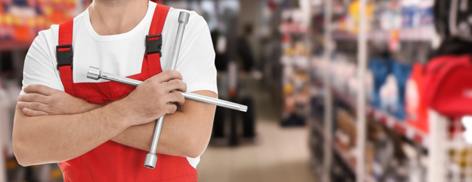 Image of Professional mechanic with lug wrench at tire shop, closeup. Banner design