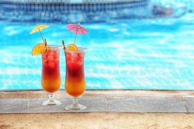 Glasses with tasty cocktails near swimming pool