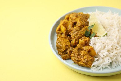 Photo of Delicious chicken curry with rice on yellow background, closeup. Space for text