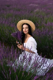 Beautiful young woman sitting in lavender field