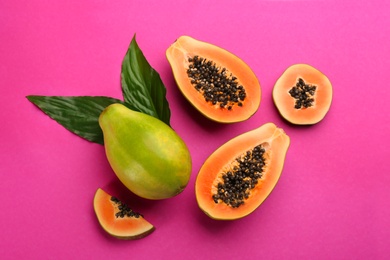 Photo of Fresh ripe papaya fruits with green leaves on purple background, flat lay