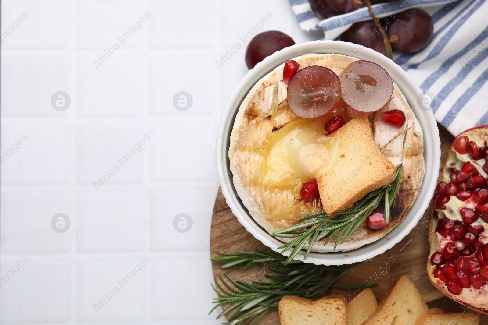 Photo of Flat lay composition with tasty baked camembert on white tiled table. Space for text