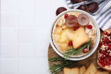 Flat lay composition with tasty baked camembert on white tiled table. Space for text