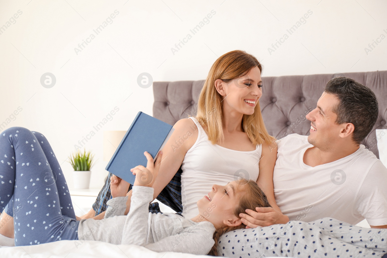 Photo of Happy family reading book with child in bedroom