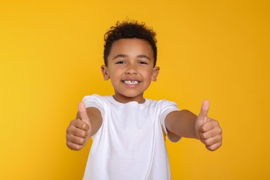 Photo of African-American boy showing thumbs up on yellow background