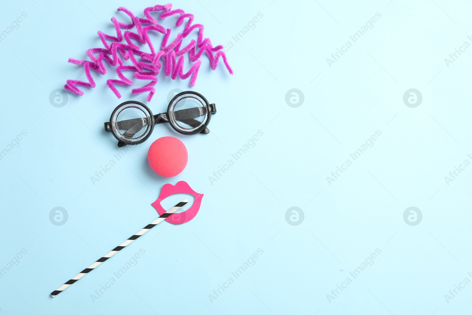 Photo of Funny face made with clown's accessories on light blue background, flat lay. Space for text