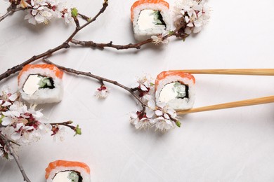 Photo of Flat lay composition of tasty sushi rolls with salmon and blossoming tree twigs on light table