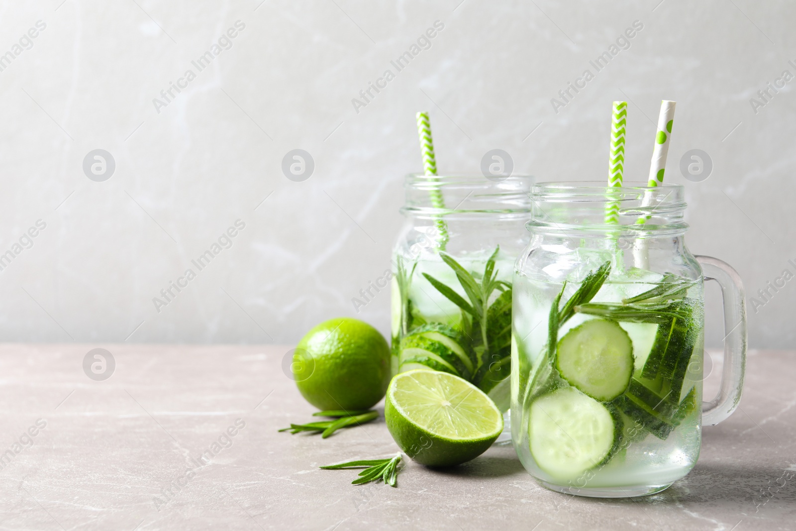 Photo of Natural lemonade with cucumber, lime and rosemary in mason jars on table