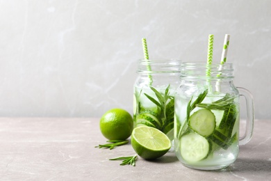 Photo of Natural lemonade with cucumber, lime and rosemary in mason jars on table