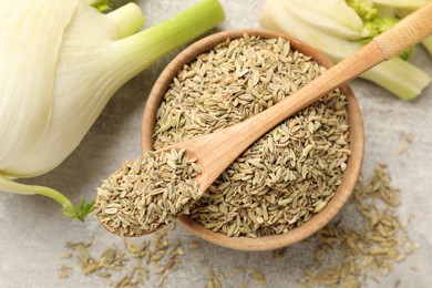 Photo of Fresh fennel bulbs, bowl and spoon with seeds on light gray table, flat lay