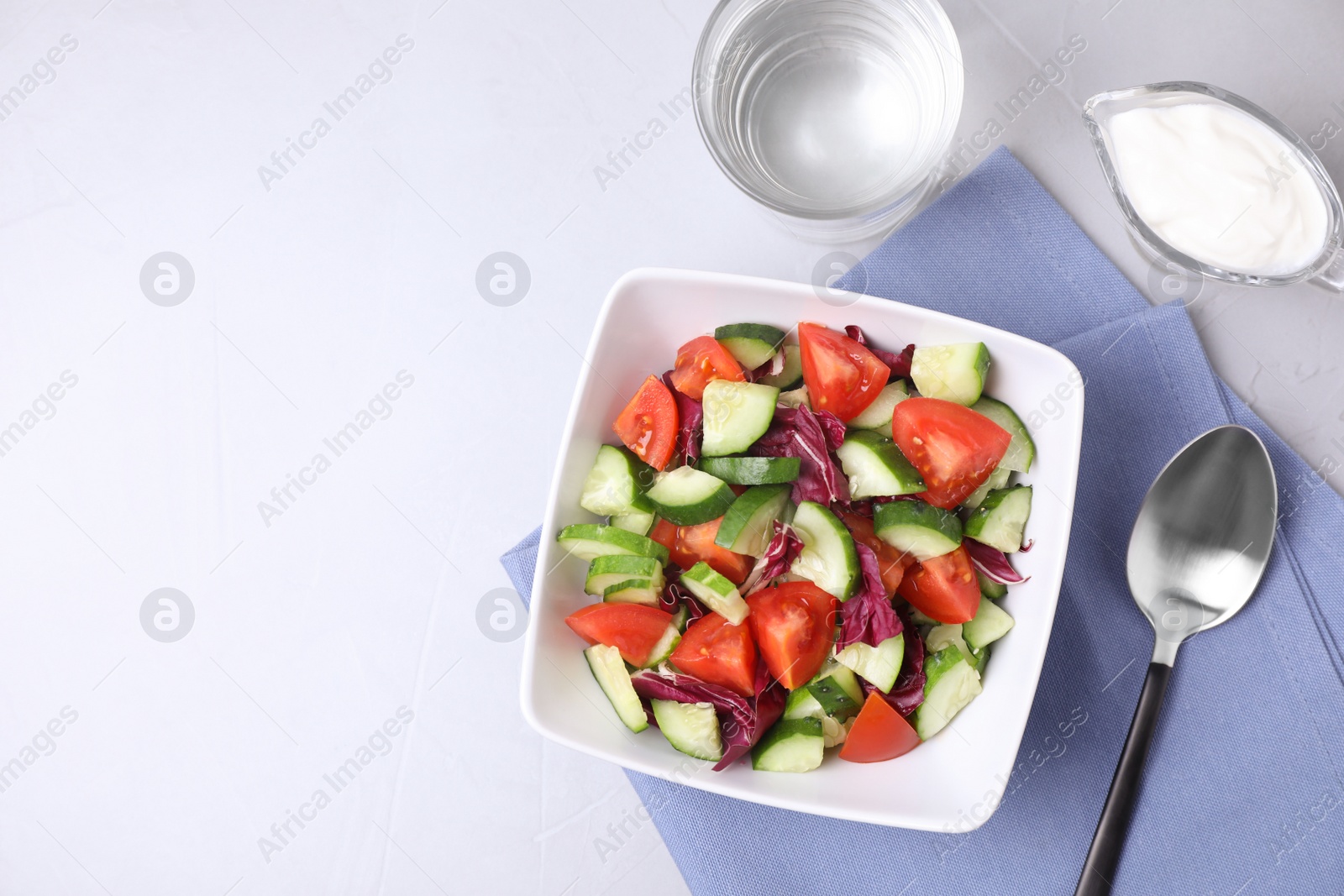 Photo of Bowl of vegetarian salad with cucumber, tomato, cabbage and onion served on table, flat lay. Space for text