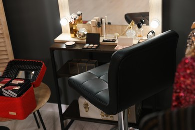 Photo of Makeup room. Chair near dressing table with different beauty products indoors