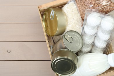 Photo of Donation box with food products on wooden table, top view. Space for text