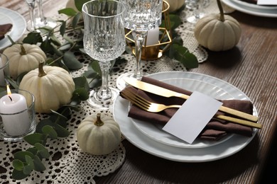 Photo of Beautiful autumn table setting. Plates, cutlery, glasses, blank card and floral decor