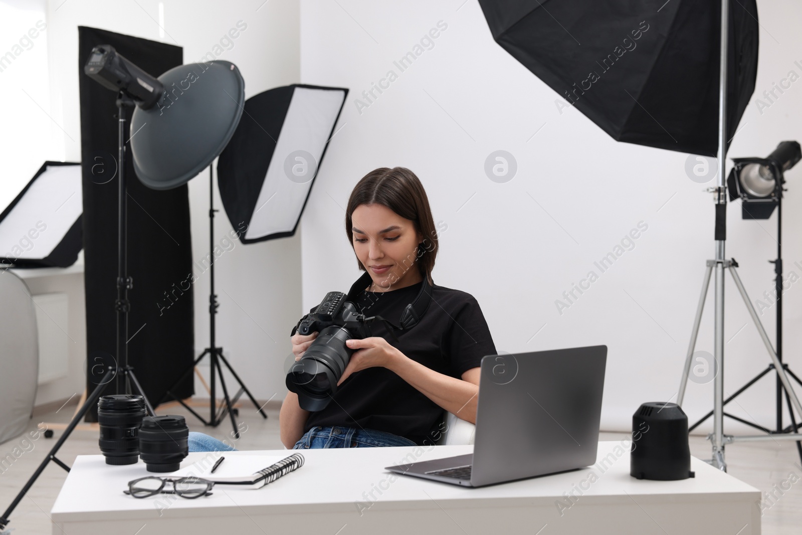 Photo of Young professional photographer with camera at table in modern photo studio