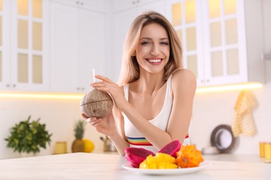 Photo of Young woman with exotic fruits in kitchen