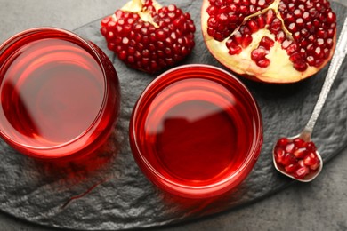 Photo of Tasty pomegranate juice in glasses and fresh fruit on grey table, top view