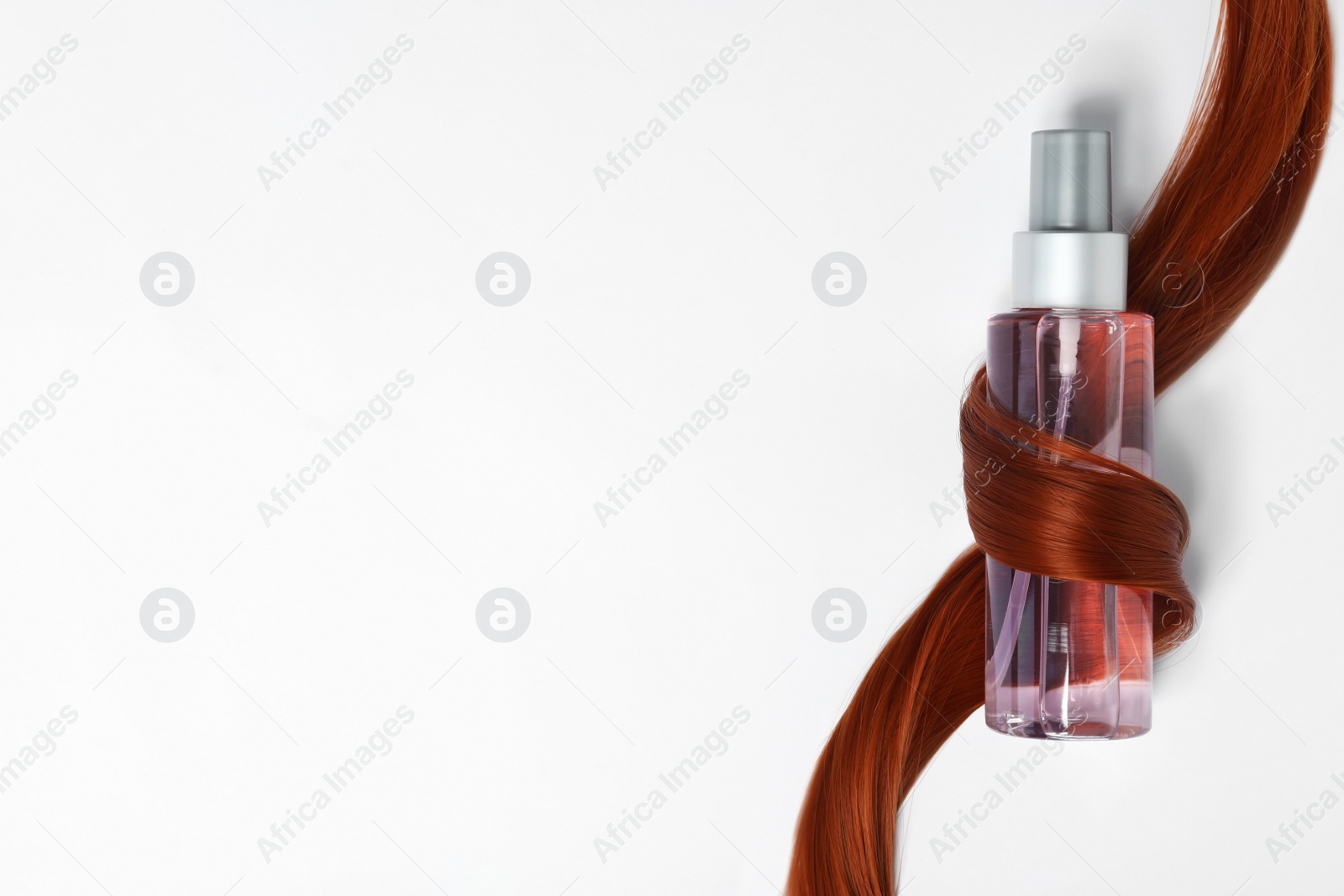 Photo of Spray bottle wrapped in lock of hair on white background, top view. Natural cosmetic products