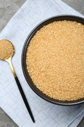 Brown sugar in bowl and spoon on table, top view