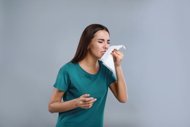 Photo of Young woman suffering from allergy on grey background