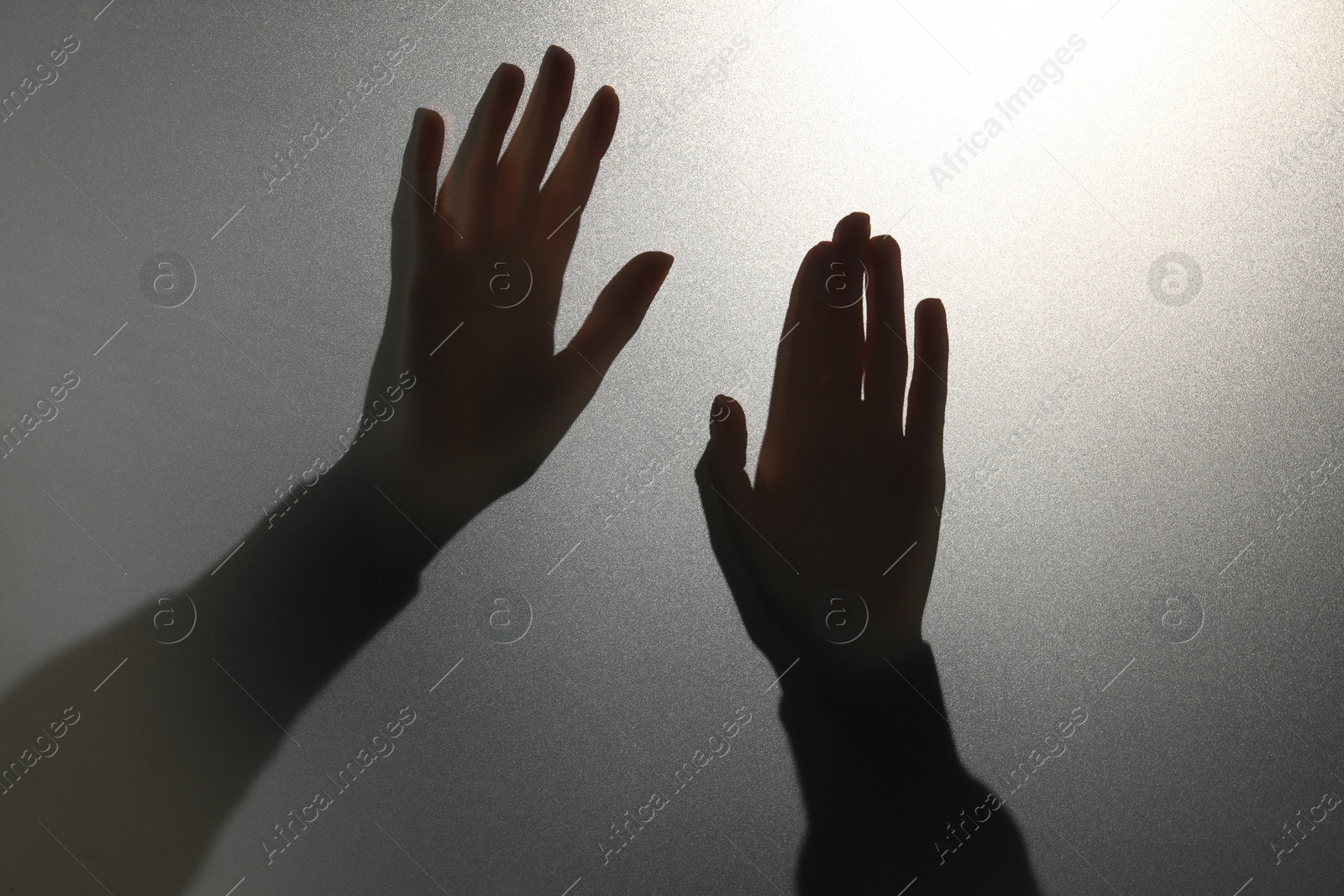 Photo of Silhouette of ghost behind glass against light grey background, closeup